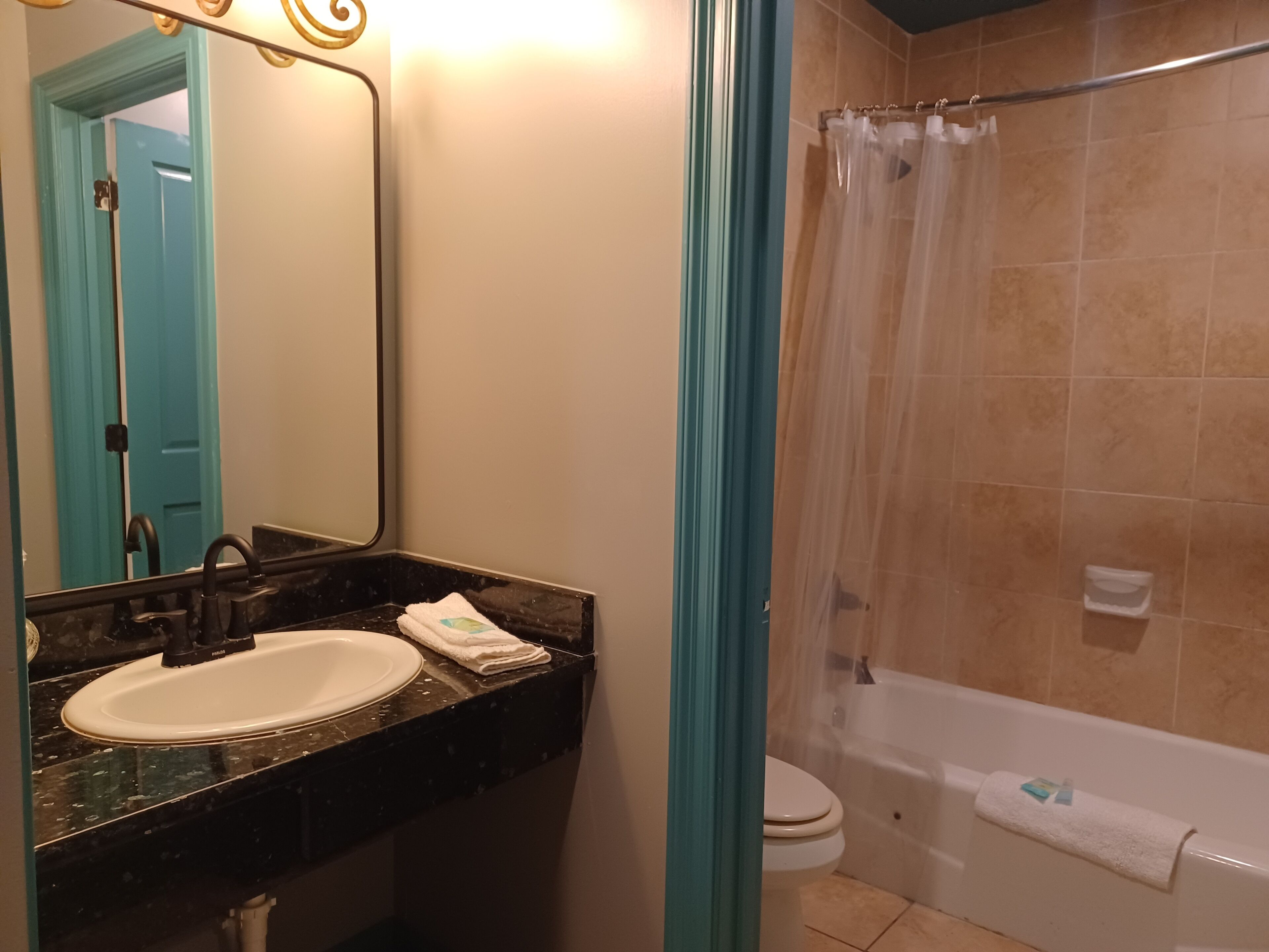 A bathroom with a sink, mirror, toilet, and bathtub.