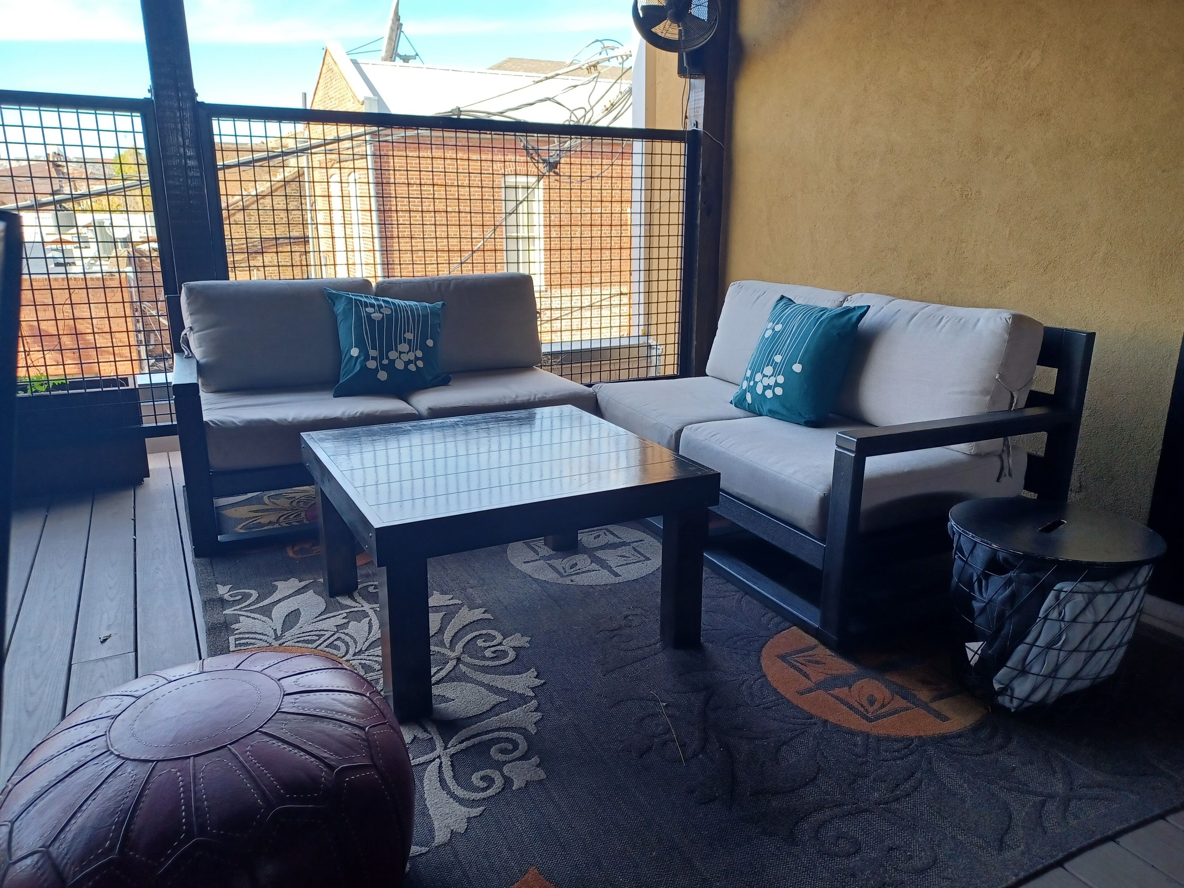 A balcony with a sofa, a coffee table, and a drum.