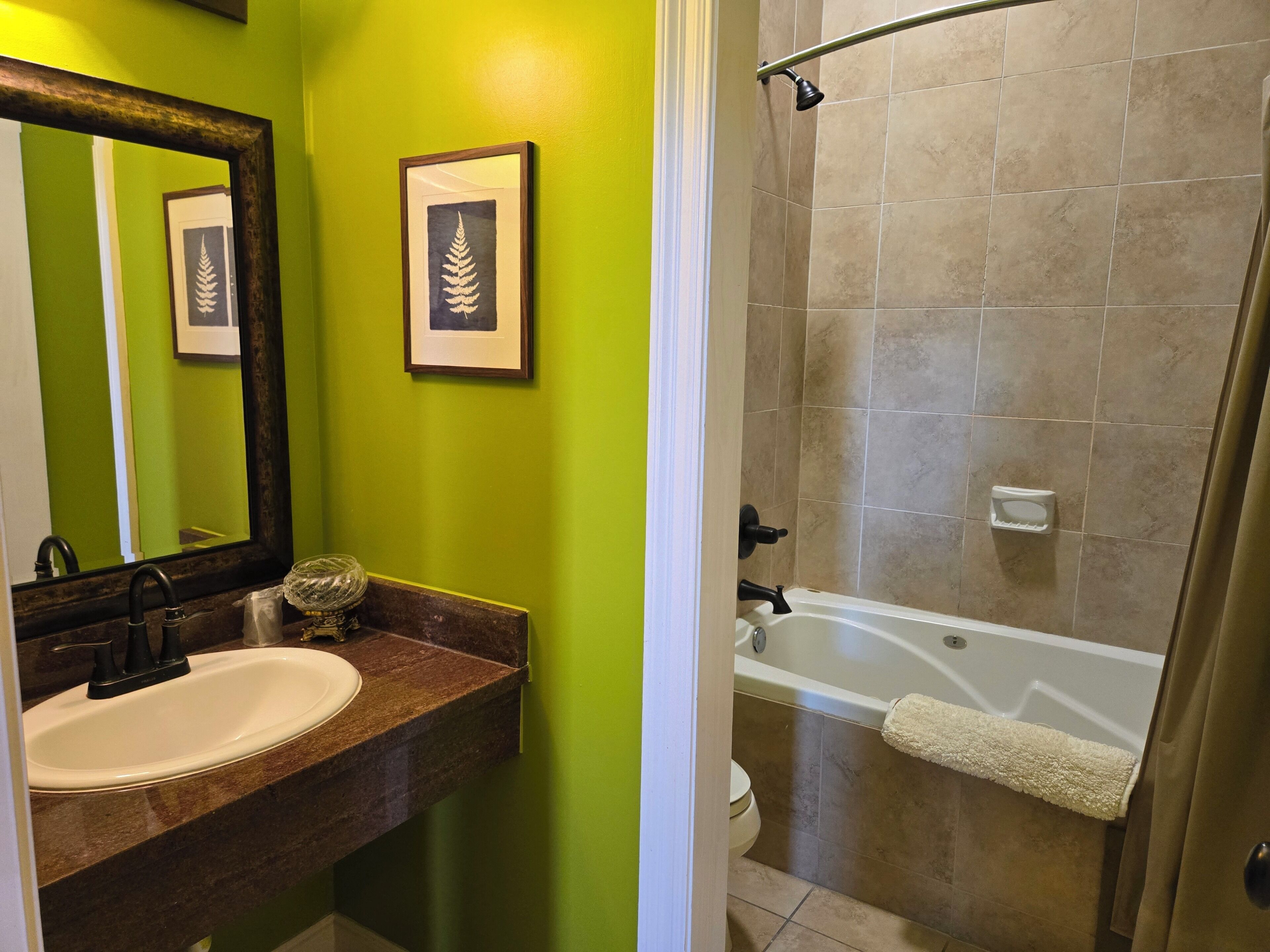 A bathroom with a sink, mirror, framed artwork, and a shower area.