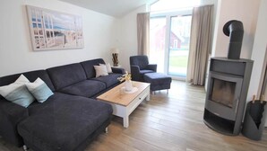 Un salon comprenant un canapé, un fauteuil, une table basse, une cheminée et un tableau accroché au mur.