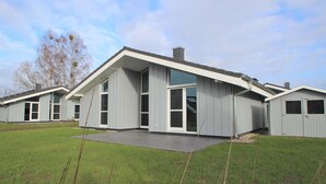 Un bâtiment moderne doté d’un toit plat, de grandes fenêtres et d’un patio couvert.