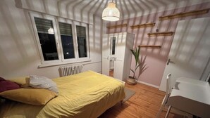 Une chambre à coucher avec un lit, un bureau, un radiateur et une fenêtre.