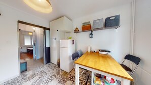 Une cuisine de taille réduite avec une table en bois, des placards blancs et un petit réfrigérateur.