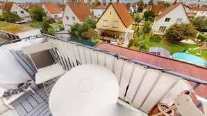 Un balcon avec une table blanche, une chaise et une petite statue.