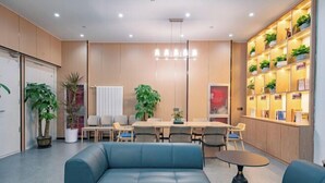 Ein moderner Arbeitsraum mit einem blauen Sofa, einem Esstisch mit Stühlen und einem Bücherregal voller Bücher und Pflanzen.