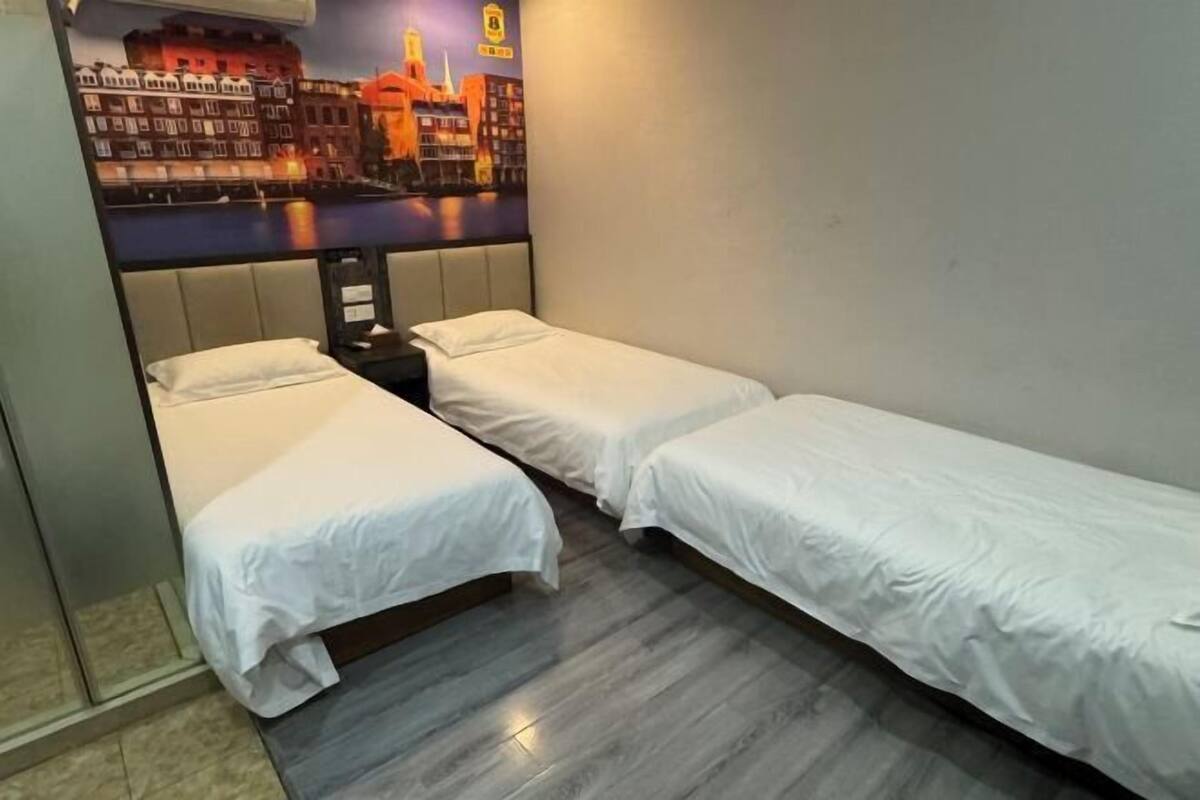 A hotel room with two single beds, a cityscape mural on the wall, and a wooden floor.