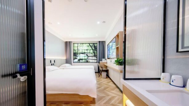 Ein modernes Hotelzimmer mit einem großen Bett, einem Schreibtisch, einem Spiegel und Blick auf Grünflächen.