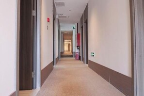 A hotel corridor with doors on both sides, a carpeted floor, and a visible exit sign. - Hanting Hotel (Beijing)