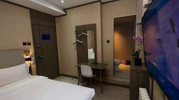 A hotel room with a bed, desk, chair, and a television.