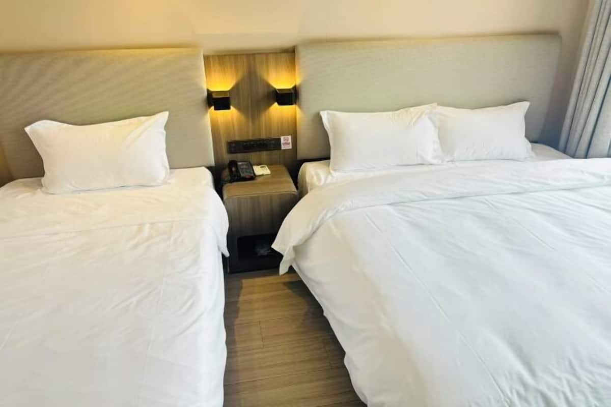 Habitación de hotel con dos camas, una mesita de noche con teléfono y lámparas fijadas a la pared.