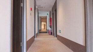 Et hotel med et tæppe belagt gulv, døre på begge sider og en skraldespand i midten.