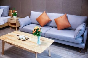A modern living room with a sofa, pillows, a coffee table, and a vase with flowers.