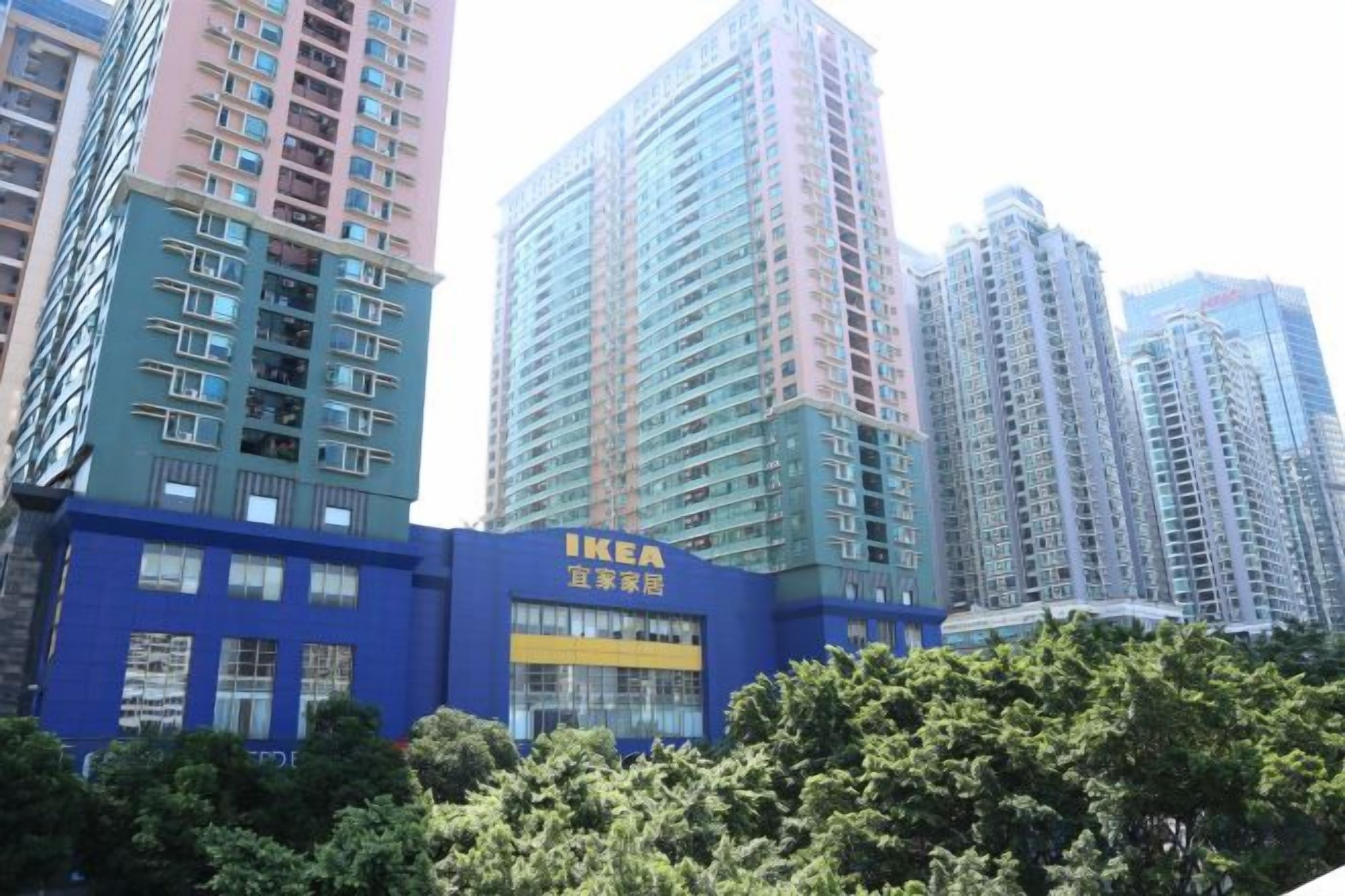 Ein mehrgeschossiges Gebäude mit blauer Fassade und dem IKEA-Logo, umgeben von Hochhäusern.