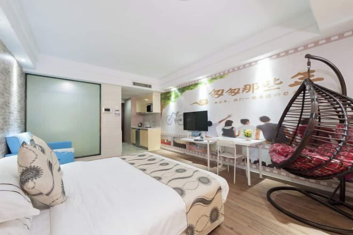 A hotel room with a bed, a desk, a chair, and a hanging chair.