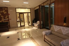 A hotel lobby with a reception desk, a sofa, and a glass door entrance.