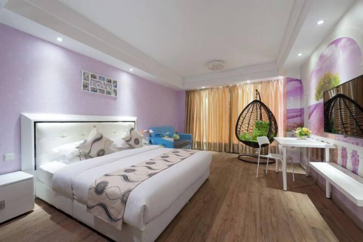 A modern bedroom with a bed, bedside table, hanging chair, and a small desk with a chair.
