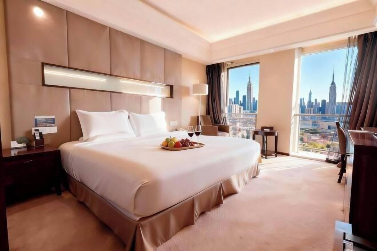A hotel room with a large bed, a city view, a desk, and a TV.