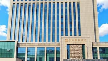 A multi-story building with a modern architectural design, featuring a prominent entrance with a decorative facade.