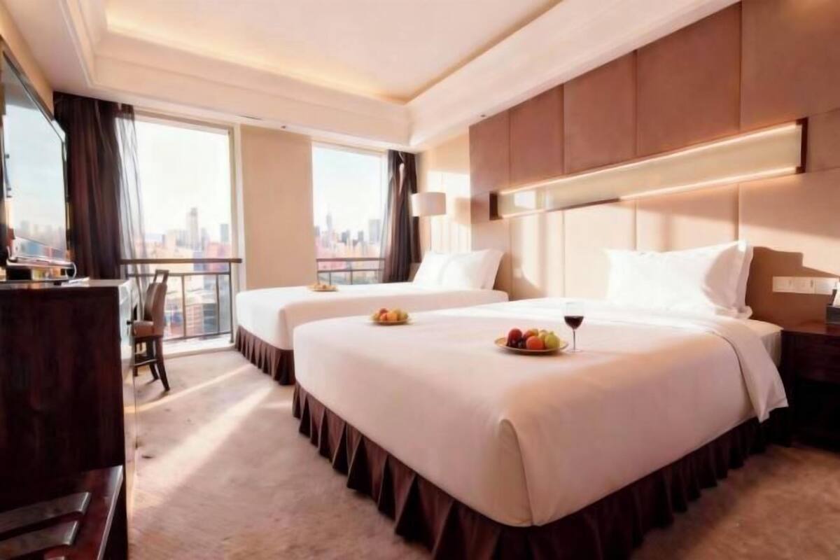 A hotel room with two beds, a city view, and a balcony.