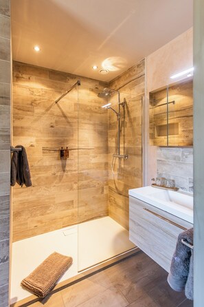 Enjoy a refreshing shower in the sleek bathroom with a glass-enclosed shower and large mirror above the sink.