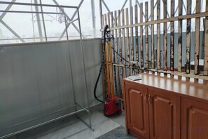 A room with a metal rack, a red vacuum cleaner, and a wooden cabinet. - Sea Trek Star Exquisite Hotel (Lishui)