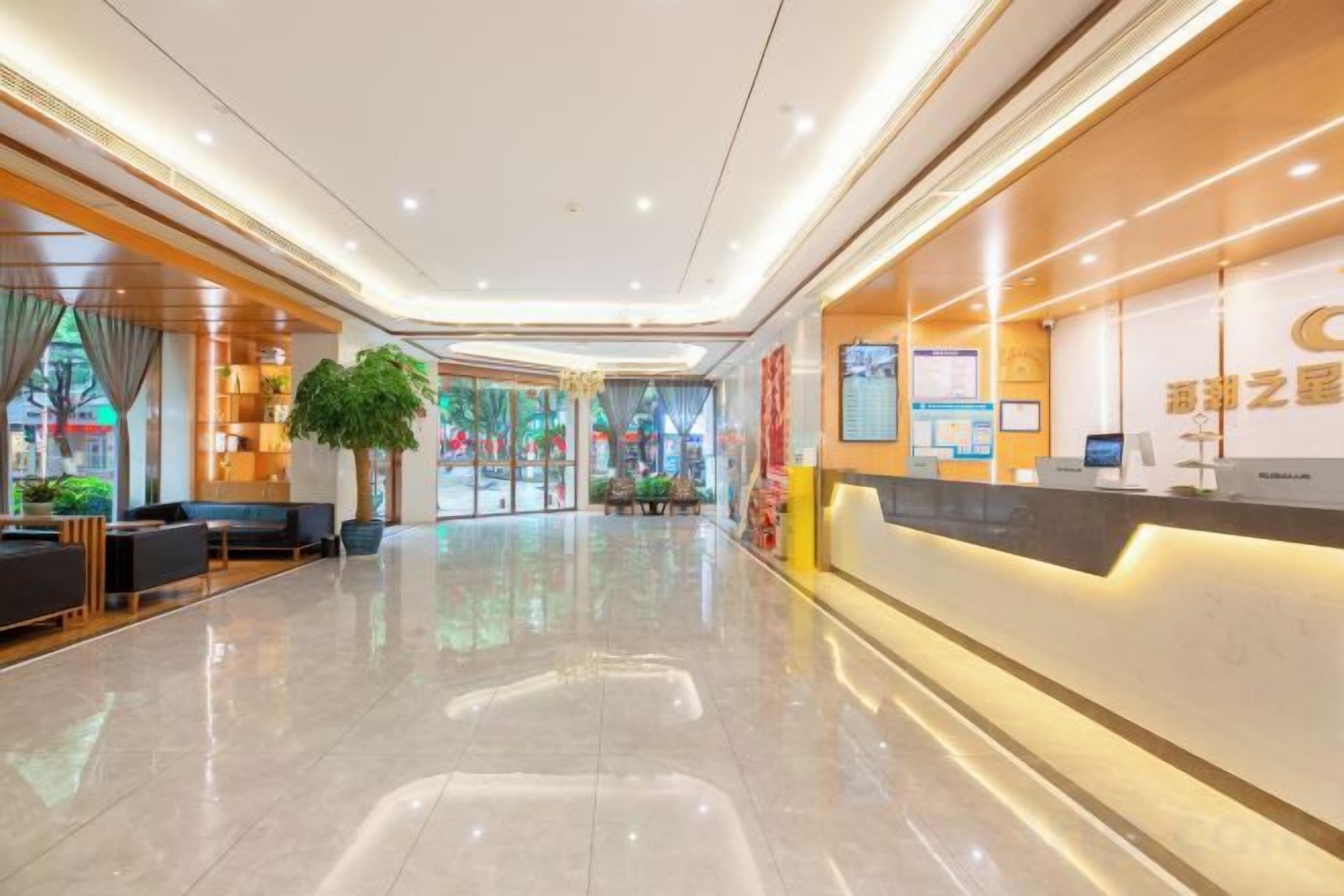 A hotel lobby with a reception desk, seating area, and a large plant.