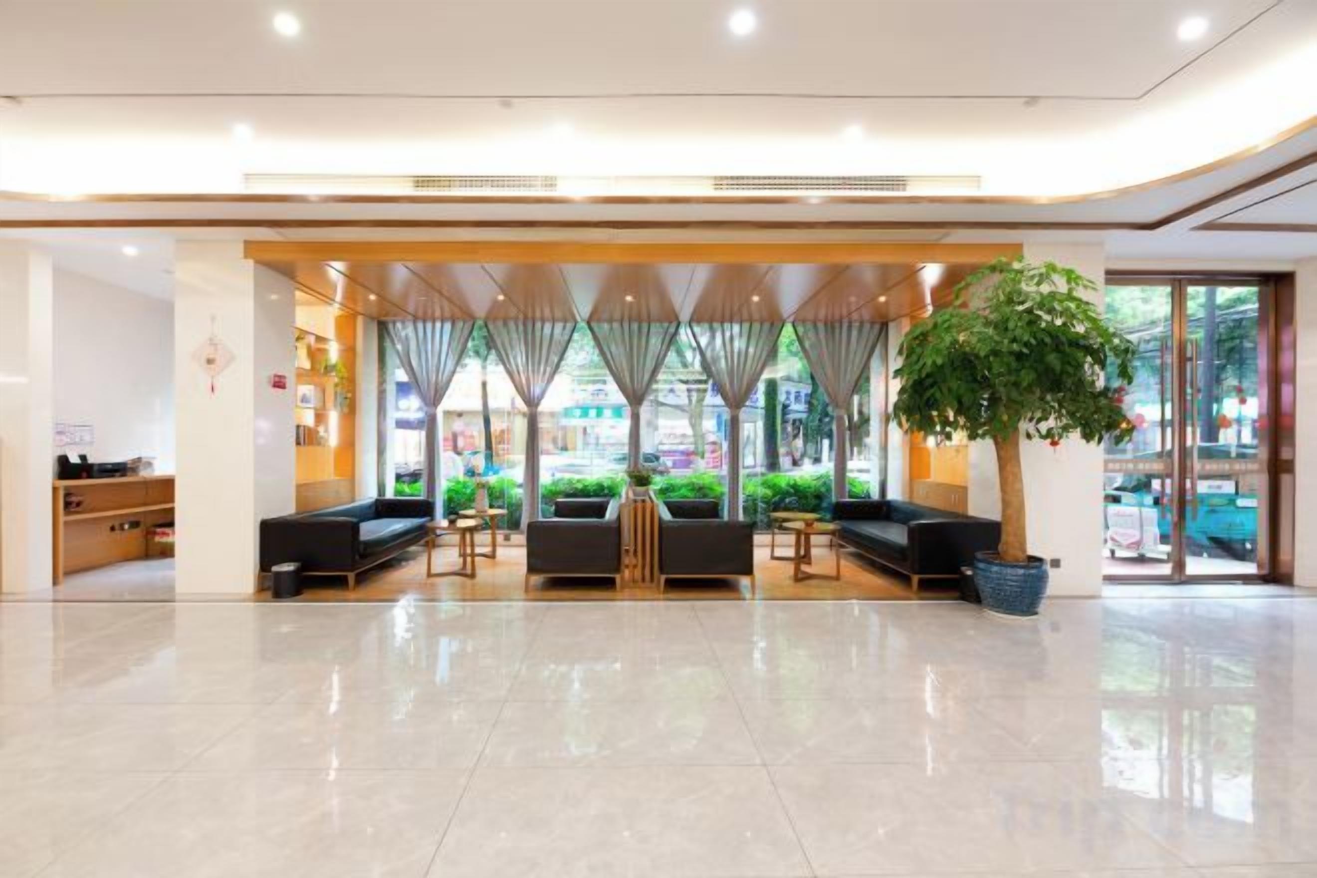 Un hall d’hôtel comprenant un comptoir d’accueil, un espace salon et une grande plante en pot.