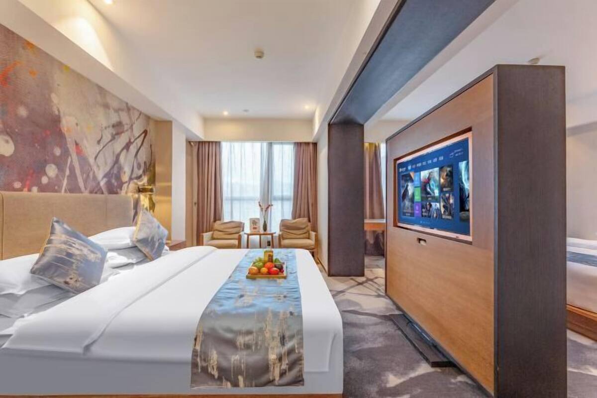 A hotel room with a bed, a TV, a desk, and a chair.