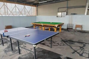 A ping pong table and a billiards table in a room with concrete flooring and a high ceiling. - Sea Trek Star Exquisite Hotel (Lishui)