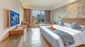 A hotel room with a bed, a desk, a TV, and a view of the city. - Sea Trek Star Exquisite Hotel (Lishui)
