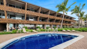 A hotel with a pool area, multiple balconies, and palm trees.