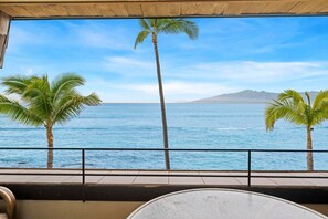 Un balcón con vista al océano y palmeras.