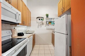 Una cocina compacta con armarios de madera, un refrigerador blanco, un microondas y una estufa.