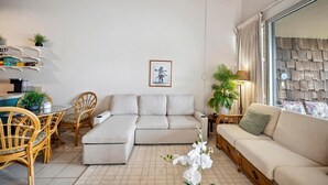 Un salon moderne comprenant un canapé, une table à manger avec des chaises et une petite table d’appoint avec une lampe.