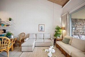 Un salon moderne comprenant un canapé, une table à manger avec des chaises et une petite table d’appoint avec une lampe.