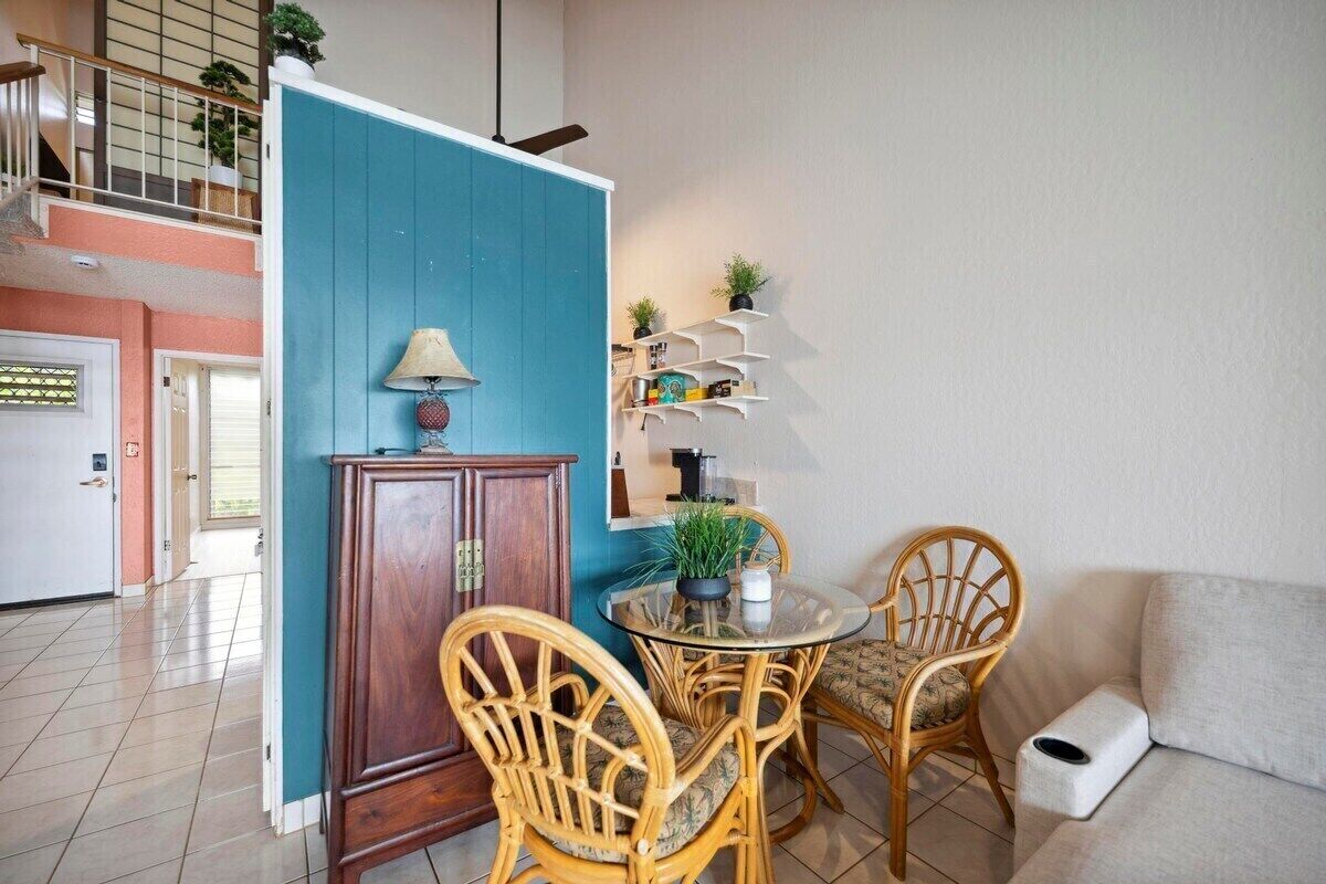 A living room with a round glass table, wicker chairs, a blue partition, and a white sofa.