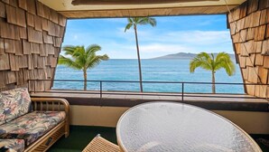 A room with a large window overlooking the ocean, featuring a sofa and a table. - Oceanfront Maui Condo-Walk to Beach, Shops, Cafés (Lahaina)