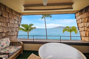 A room with a large window overlooking the ocean, featuring a sofa and a table.