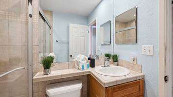 A modern bathroom with a shower, toilet, sink, and wooden vanity.