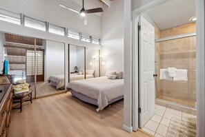 Un dormitorio moderno con una cama grande, un vestidor y una ducha de vidrio.