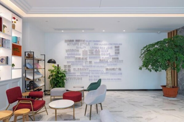 A modern lounge area with comfortable seating, a projection wall with motivational phrases, and a potted plant. - Magnotel (Qinzhou)