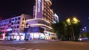 A multi-story hotel with illuminated signage and a prominent entrance. - Magnotel (Qinzhou)