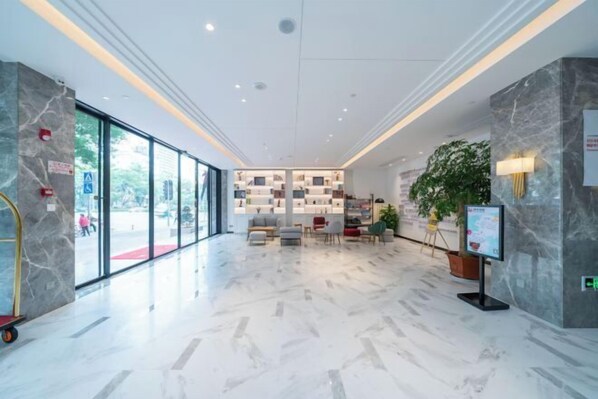 A spacious lobby with a marble floor, seating area, and a reception desk. - Magnotel (Qinzhou)