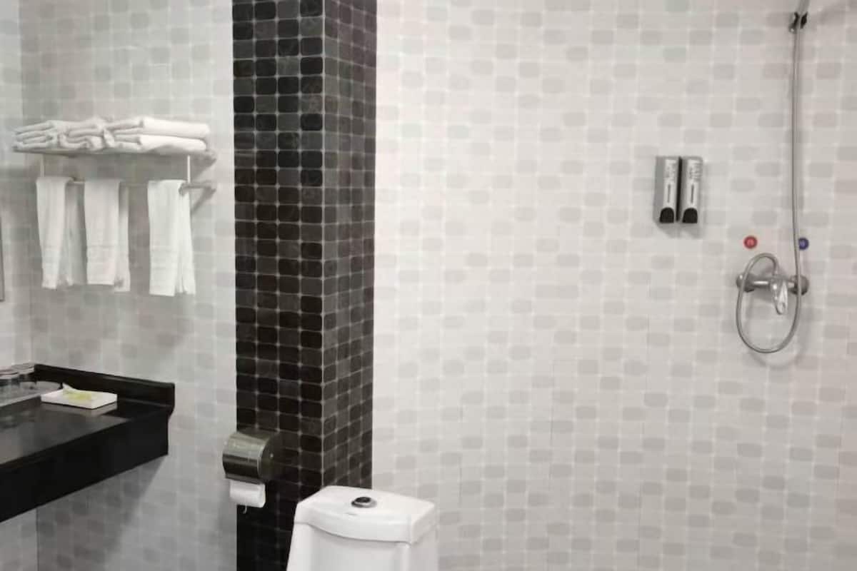 A bathroom with a black tiled column, a sink with a black countertop, and a shower with a handheld showerhead.