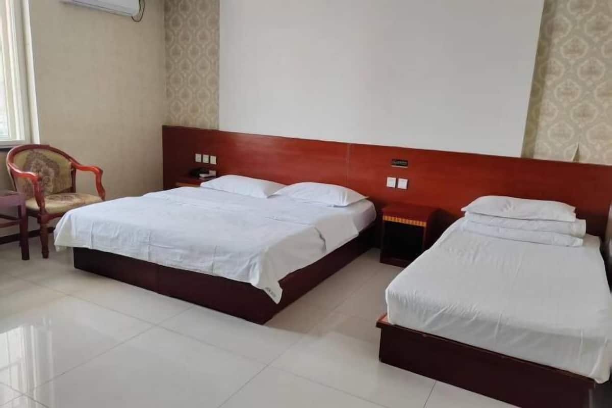 A hotel room with two beds, a chair, and a nightstand.