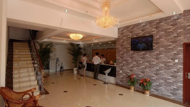 Eine Hotellobby mit einer Rezeption, einer Treppe und einer Kronleuchter.