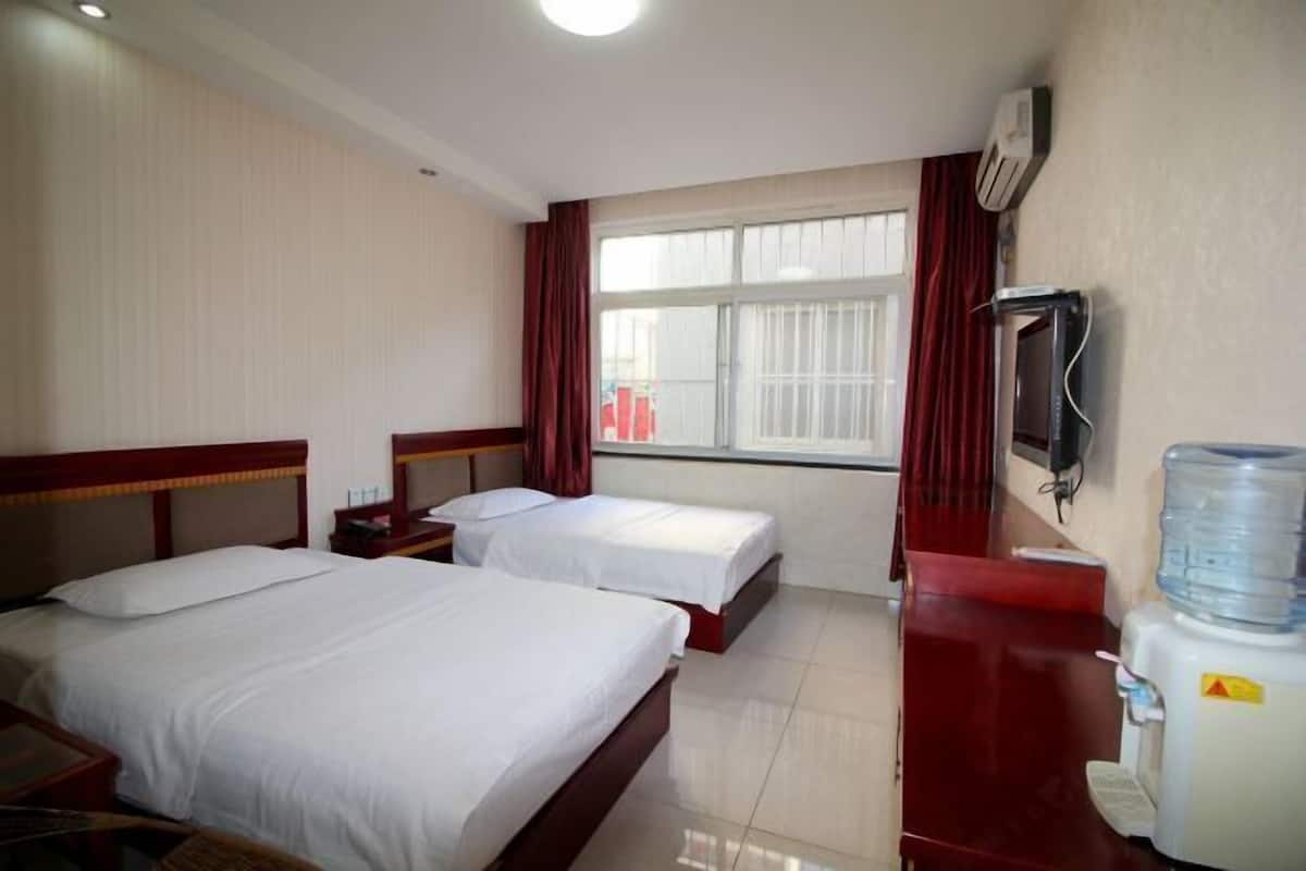 A hotel room with two beds, a water dispenser, and a TV on the wall.