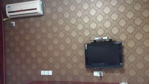 Ein Zimmer mit gestreiftem Wandteppich, einem Wand-Fernseher und einer Klimaanlage.