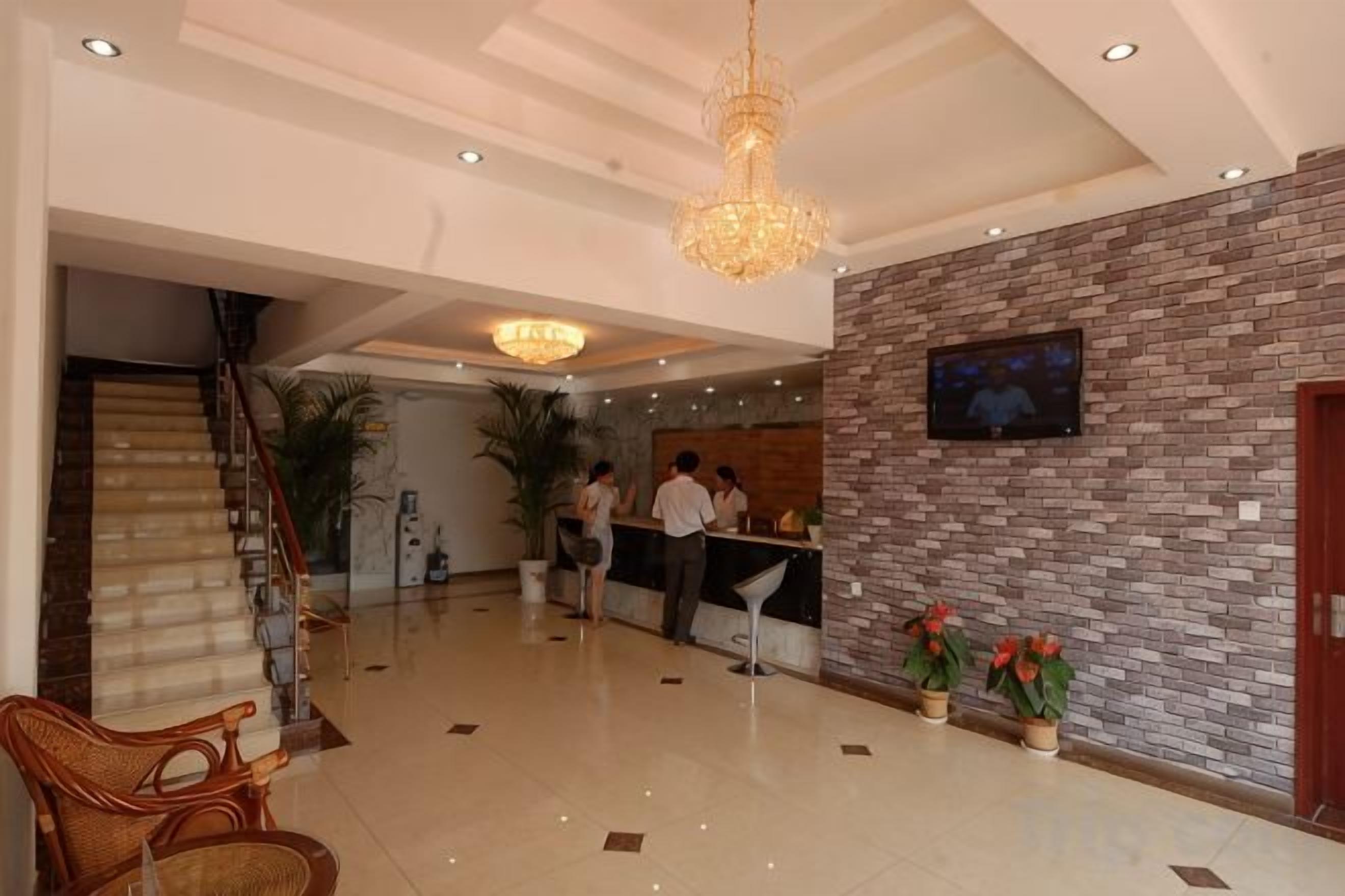 Een hotel lobby met een receptiebalie, een trap en een kroonluchter.