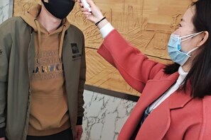 A person wearing a red jacket interacting with another individual in a casual setting. - Youdian Hotel (Zhaoyuan)